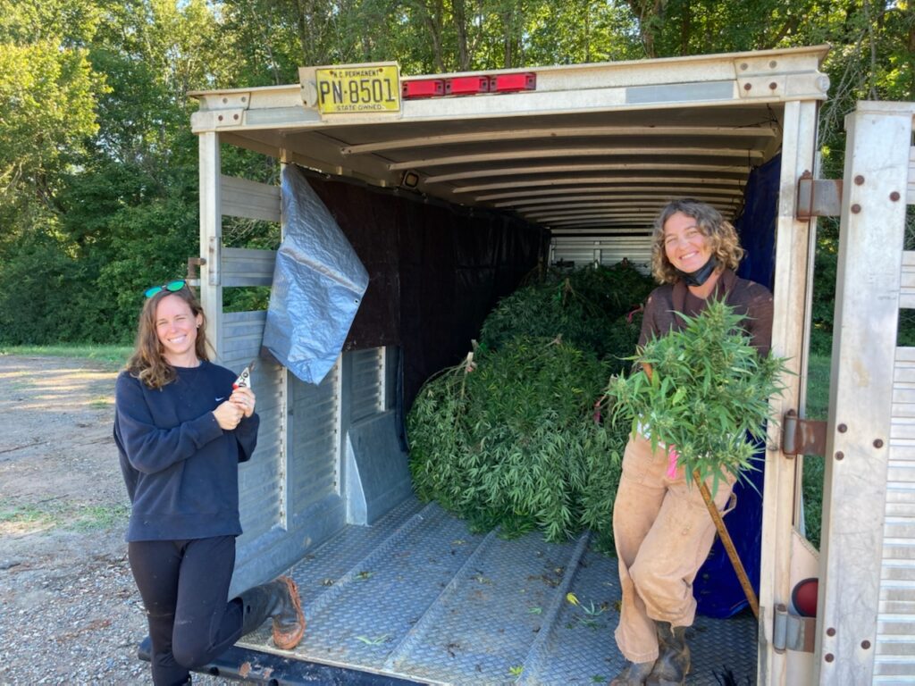 two women with trailer of harvested hemp